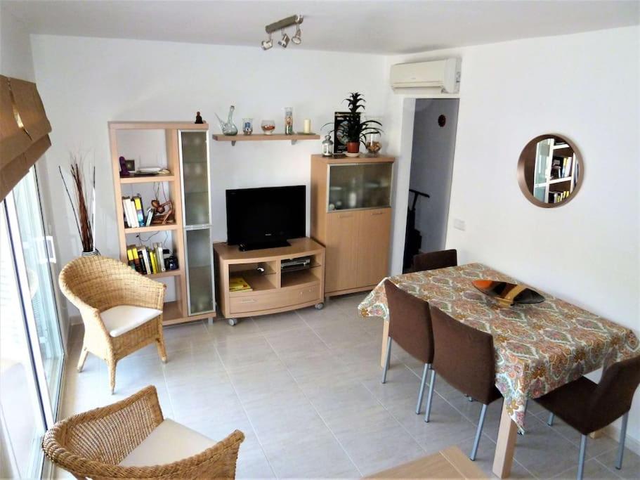 een woonkamer met een tafel en een televisie bij Centrally located apartment with free A/C + WIFI in L'Estartit