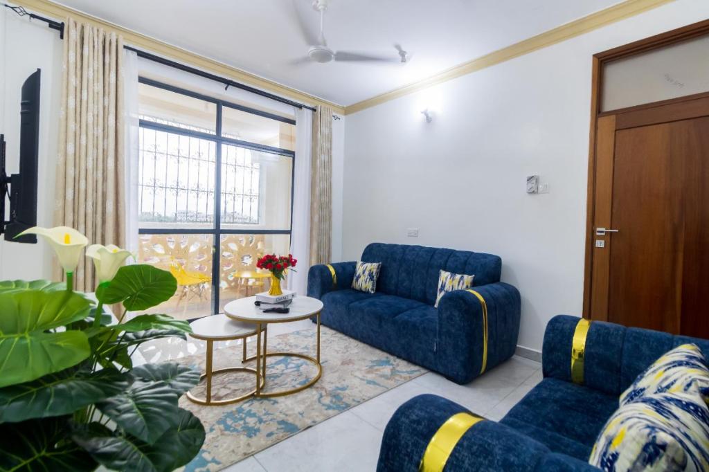 a living room with blue couches and a table at Mombasa Comfy Stay Bamburi 1br in Mombasa