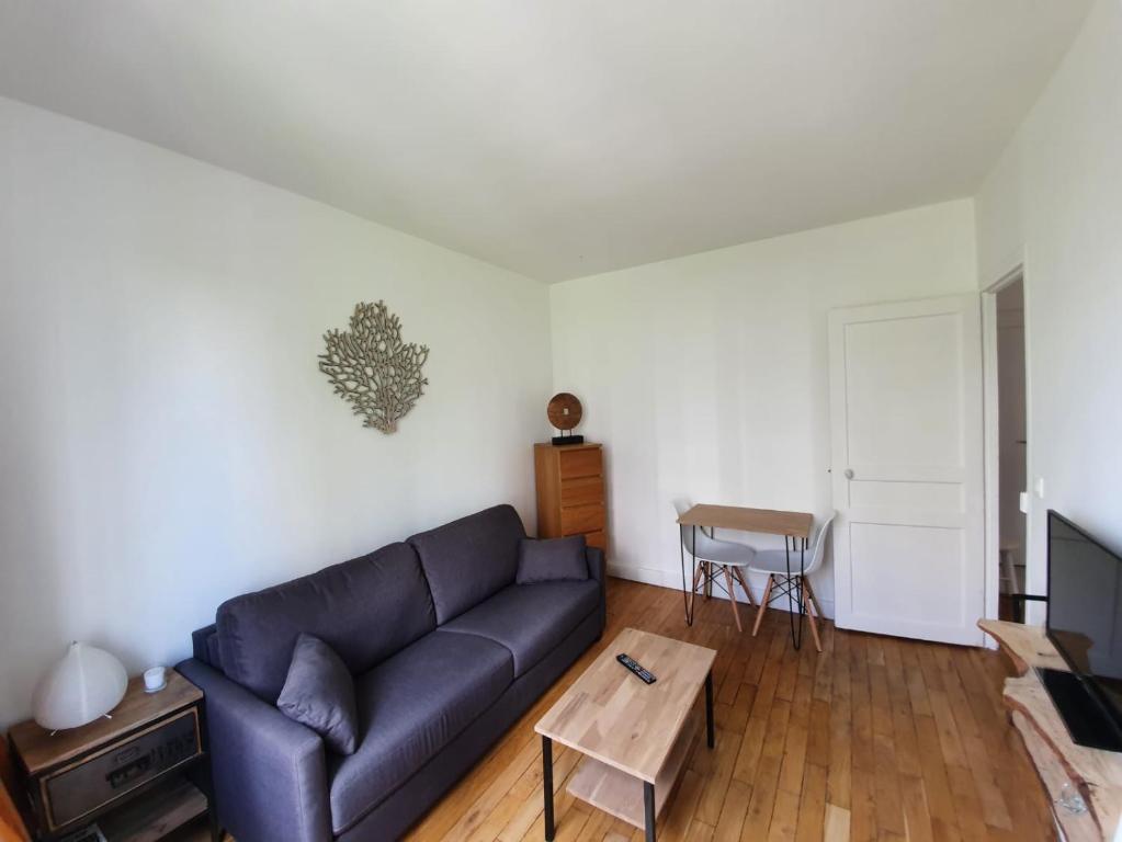 een woonkamer met een bank en een tafel bij Chambre privée dans magnifique appartement calme in Parijs