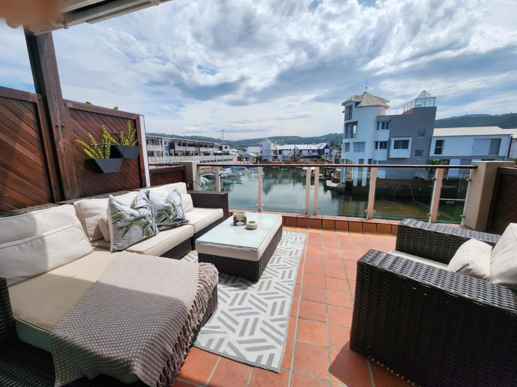 a patio with couches and a table on a balcony at Quay Five on the Waterfront in Knysna