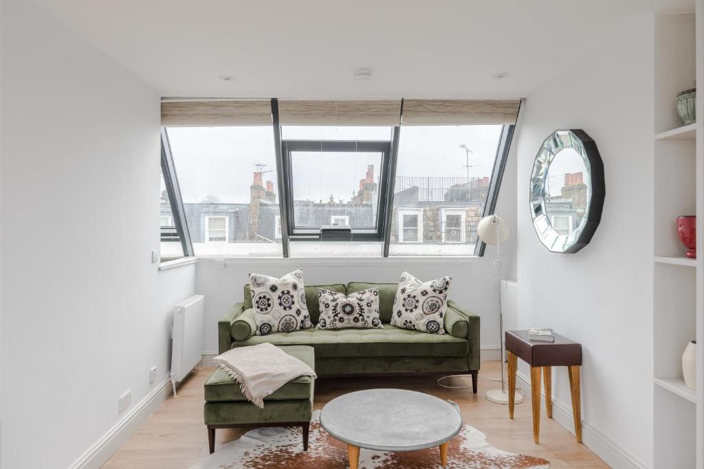 a living room with a green couch and two windows at Light-filled Primrose Hill Rooftop Retreat in London