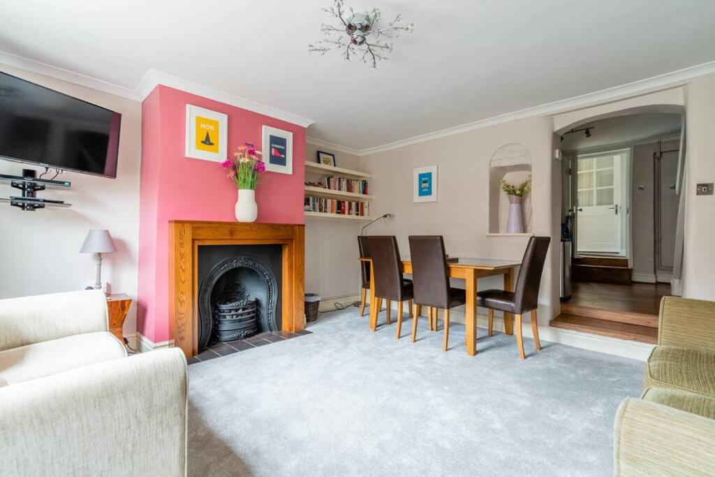 a living room with a table and a fireplace at Arnica Cottage in Wells next the Sea