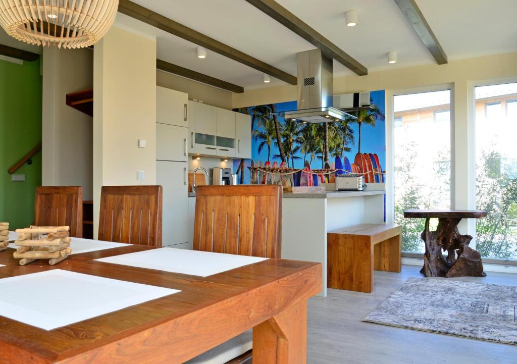 a dining room with a wooden table and a kitchen at Typ A Ferienhaus - Kailua in Pelzerhaken