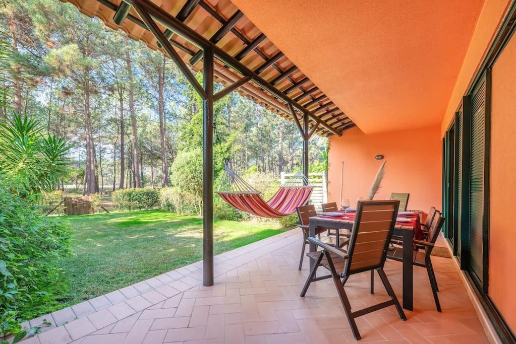 un patio con mesa, sillas y hamaca en Casa do Jardim- Aroeira en Aroeira