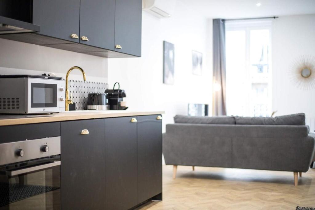 a kitchen and living room with a couch and a microwave at Appartement luxueux proche Arc-de-Triomphe - 4P in Paris