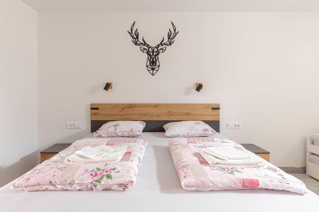 1 dormitorio con 2 camas con sábanas rosas y una cabeza de ciervo en la pared en Apartma Naravni biser, en Brezje