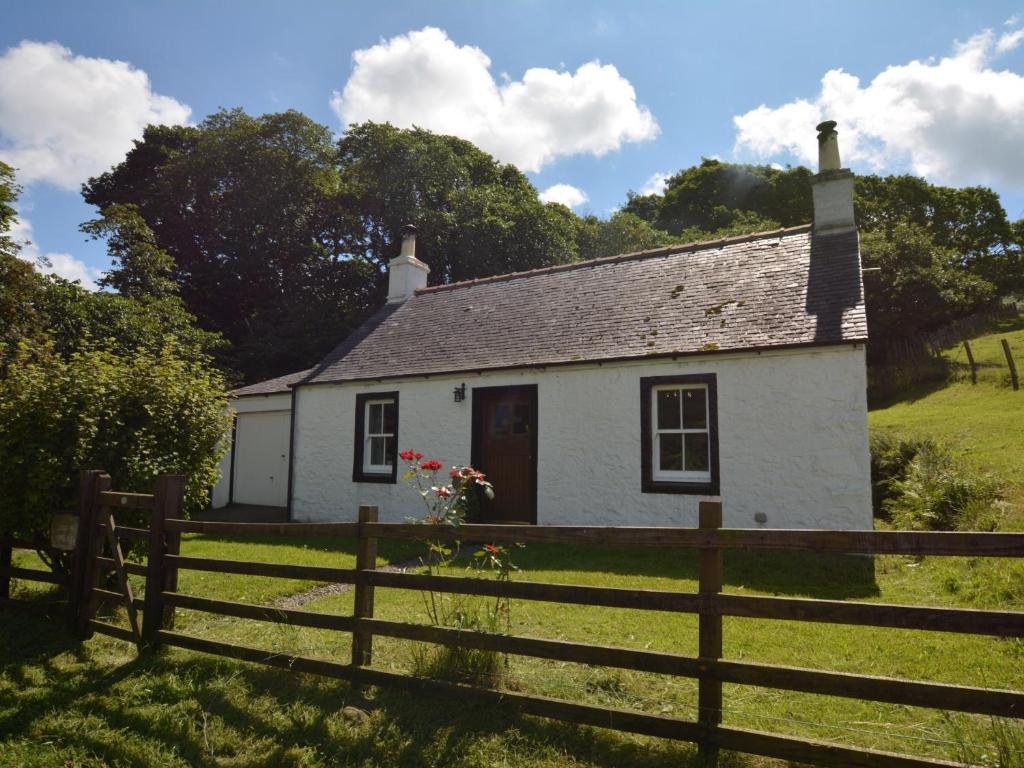 a white cottage in a field with a fence at 1 Bed in Ballantrae 45713 in Ballantrae