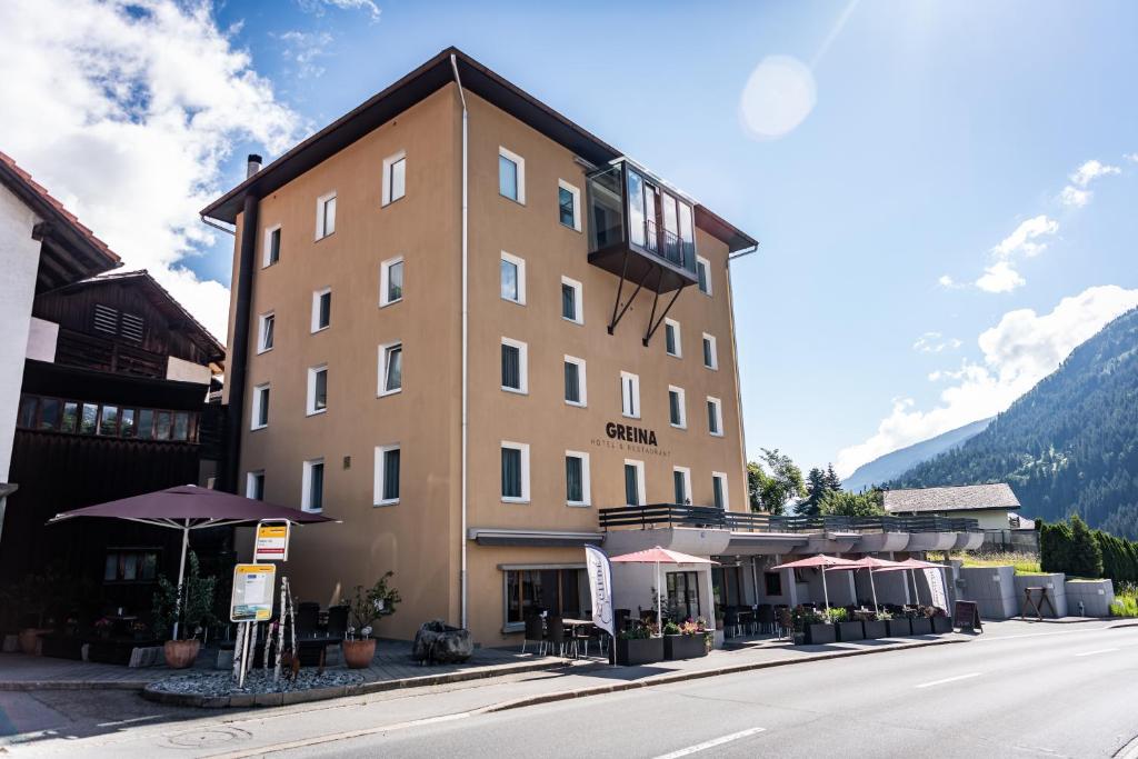 a large brown building with umbrellas on a street at Hotel Greina in Rabius