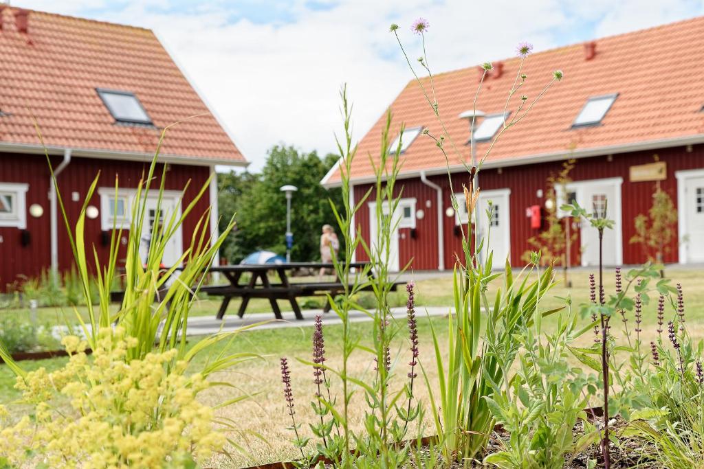 two red buildings with a picnic table in the background at Apelviken Lägenhetshotell in Varberg