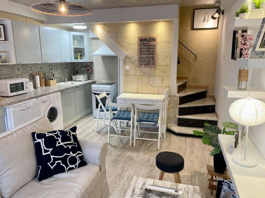 een woonkamer en een keuken met een bank en een tafel bij Rare Maison au centre ville avec terrasse et clim Arles Camargue in Arles