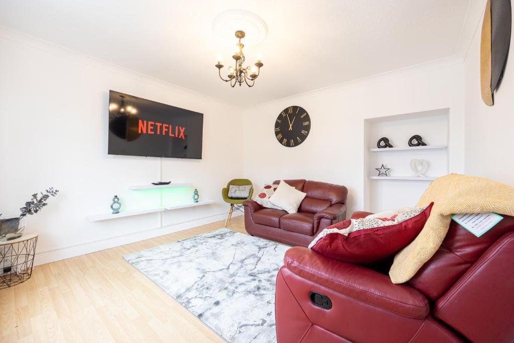 a living room with a red couch and a tv at Entire 3 bedrooms home away from Home in Salford in Manchester