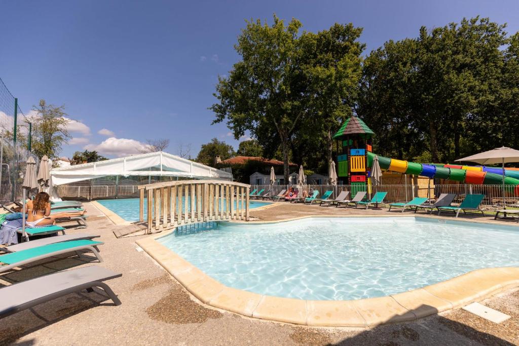 a swimming pool with a water slide and chairs at Camping maeva Club Royal Océan in Saint-Sulpice-de-Royan