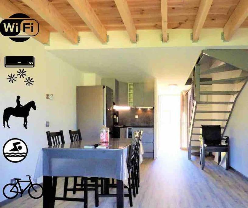 una cucina e una sala da pranzo con tavolo e un cavallo sul muro di Appartement wifi, piscine, spa, clim, +vélo à Arles en Camargue pour 6 pers a Arles