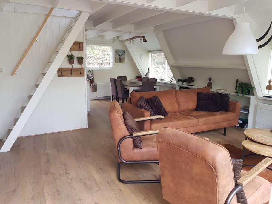 ein Wohnzimmer mit braunen Ledermöbeln und einer Treppe in der Unterkunft Vakantiehuisje familytime - Chalet 122 in Durbuy