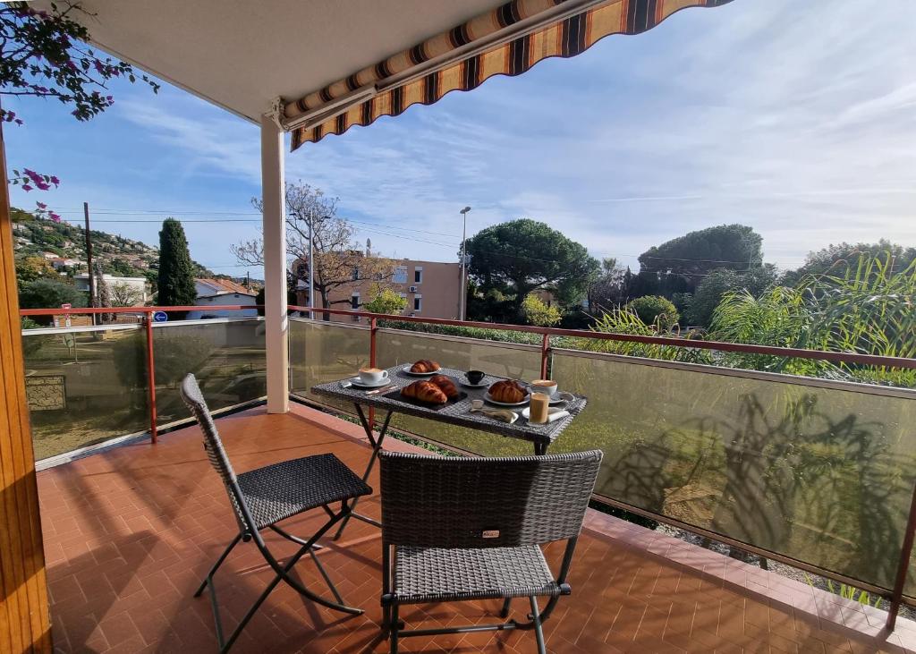 - un balcon avec 2 chaises et une table avec de la nourriture dans l'établissement Les Hippocampes - T2 avec clim et parking, au Lavandou