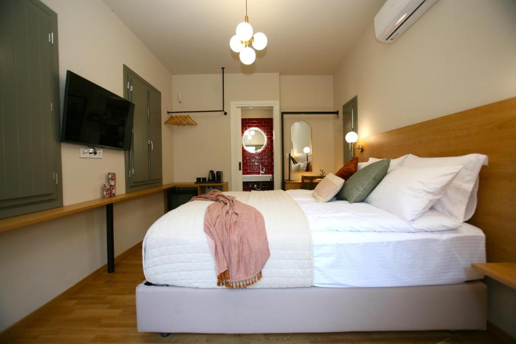 a bedroom with a white bed and a flat screen tv at Living Yard Acropolis in Athens