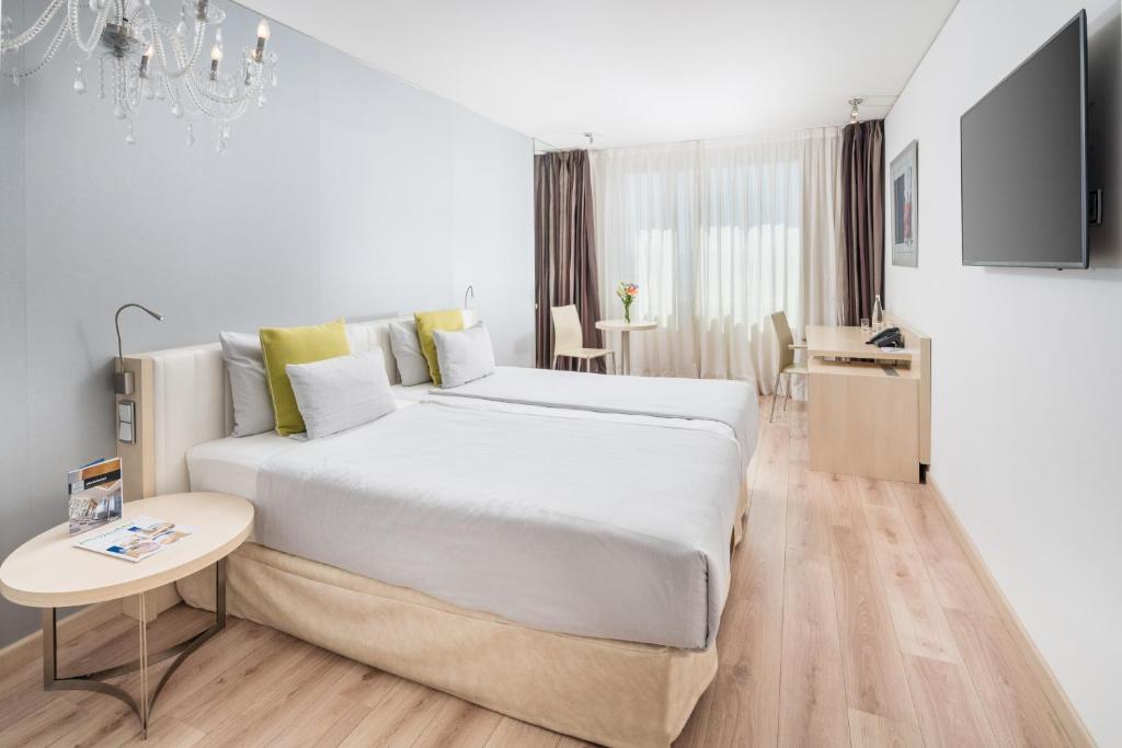 een witte slaapkamer met een groot bed en een tafel bij Abba Berlin Hotel in Berlijn