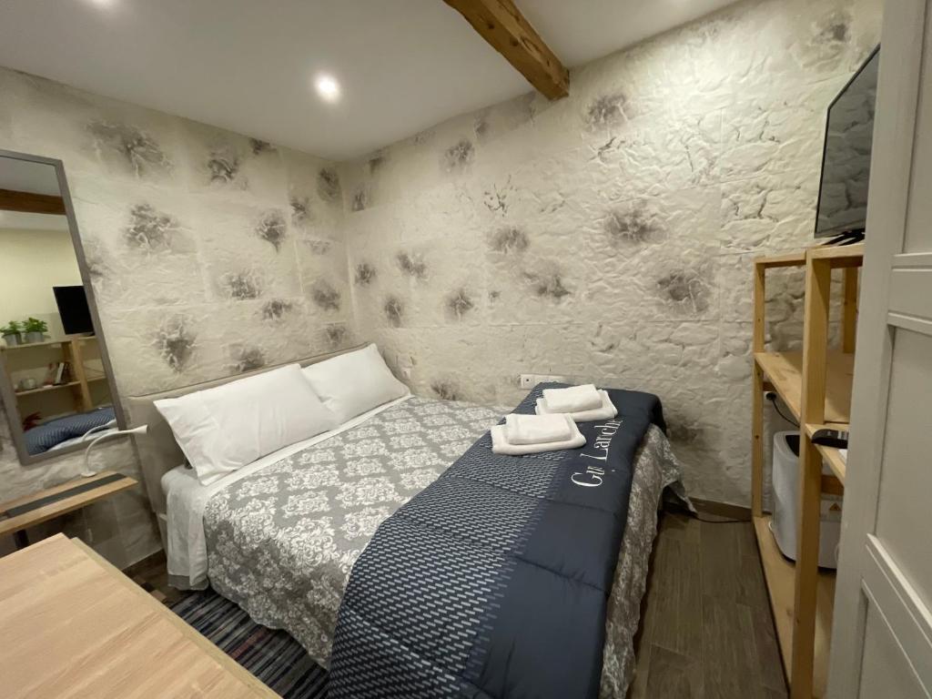 een kleine slaapkamer met een bed en een muur bij Corfu Old Town’s Cutiest Place in Corfu-stad