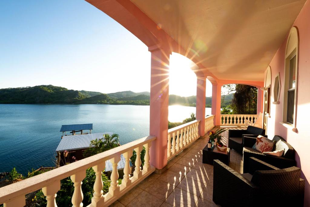 un balcón de una casa con vistas al agua en El Palacio Rosa on Blue Lagoon 3BR Beachfront Suite on pristine & quiet bay w incredible views, en Arrozal
