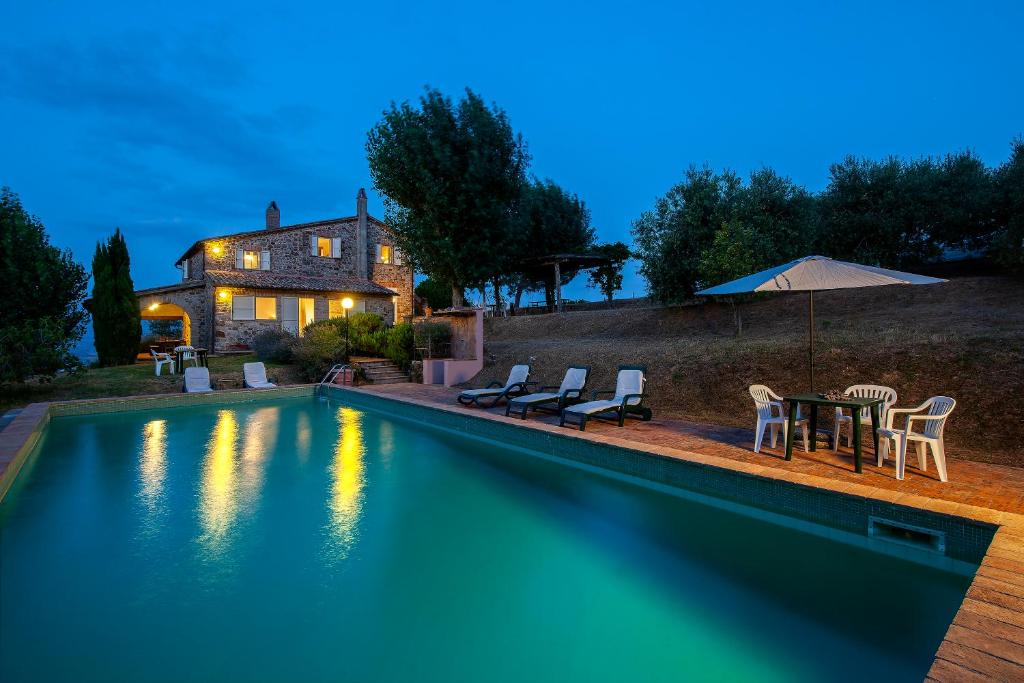 a swimming pool with chairs and a table and a house at Villa degli Artisti by Mmega in Canonica