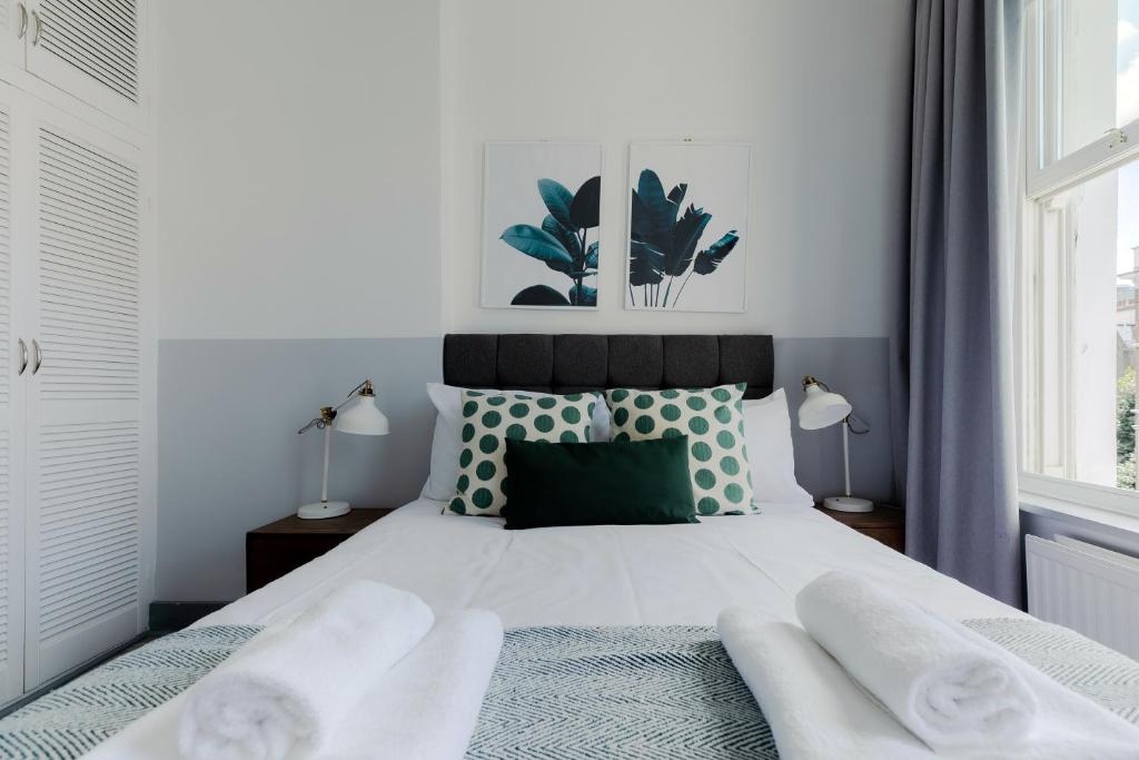 een slaapkamer met een bed met groene en witte kussens bij Modern Kensington Apartments in Londen