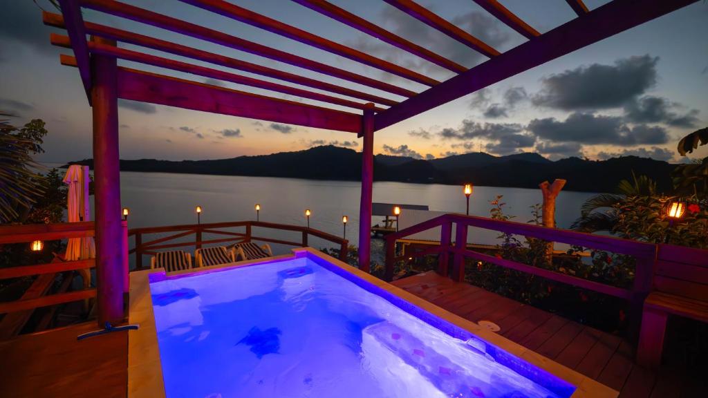 Arrozal的住宿－El Palacio Rosa on Blue Lagoon 2BR Beachfront Suite on pristine & quiet bay w incredible views，享有水景的甲板上的热水浴池