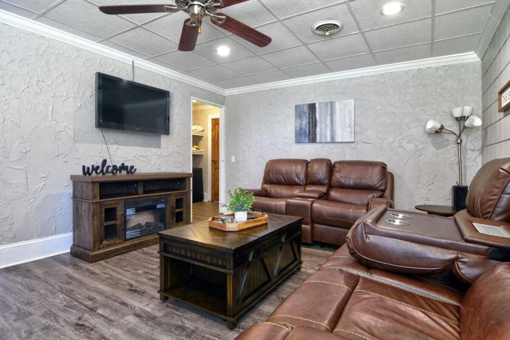 een woonkamer met lederen meubels en een flatscreen-tv bij Amazing Cottage - Located on Blue Mile - Close to GSU! in Statesboro