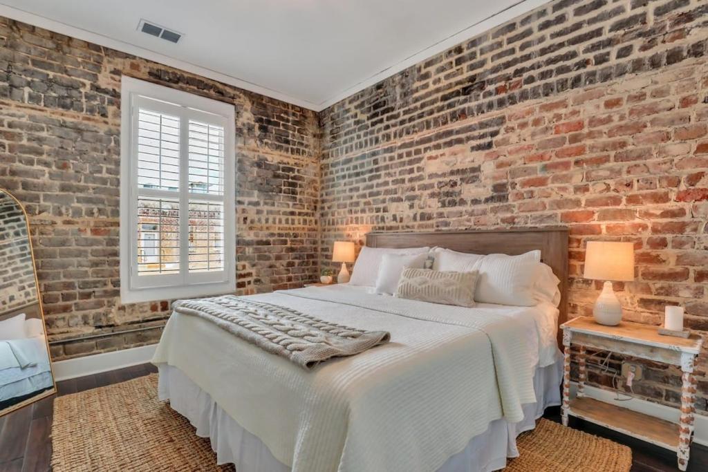Un dormitorio con una pared de ladrillo y una cama. en Broughton Street Bungalow - Steps to Everything, en Savannah