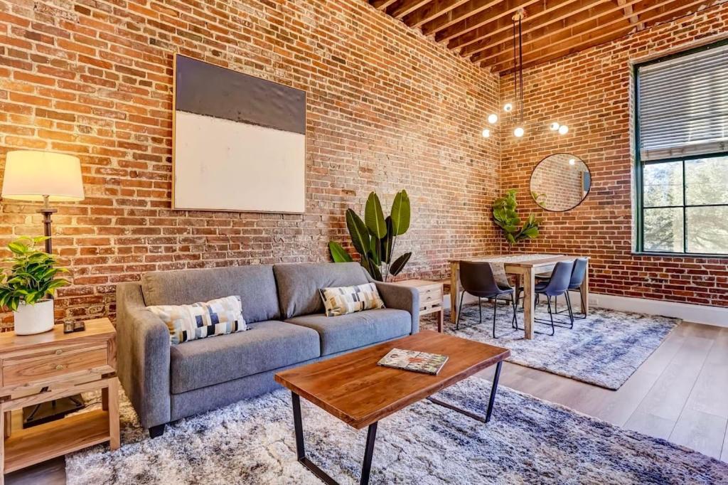 a living room with a couch and a brick wall at West End Loft - Downtown 5 min walk to River St in Savannah
