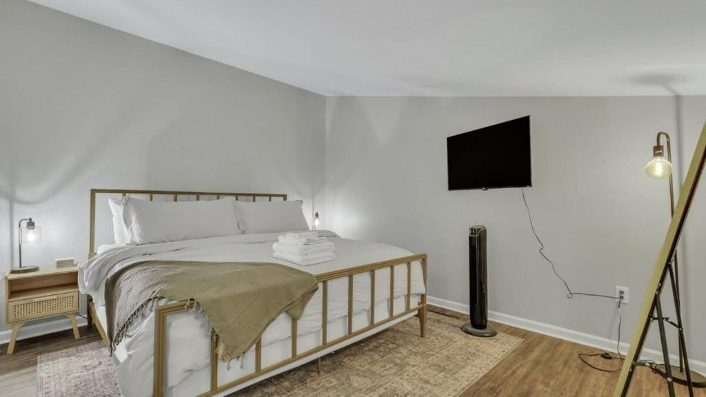 a bedroom with a bed and a flat screen tv at Eagle's Roost Retreat - Near GSU in Statesboro