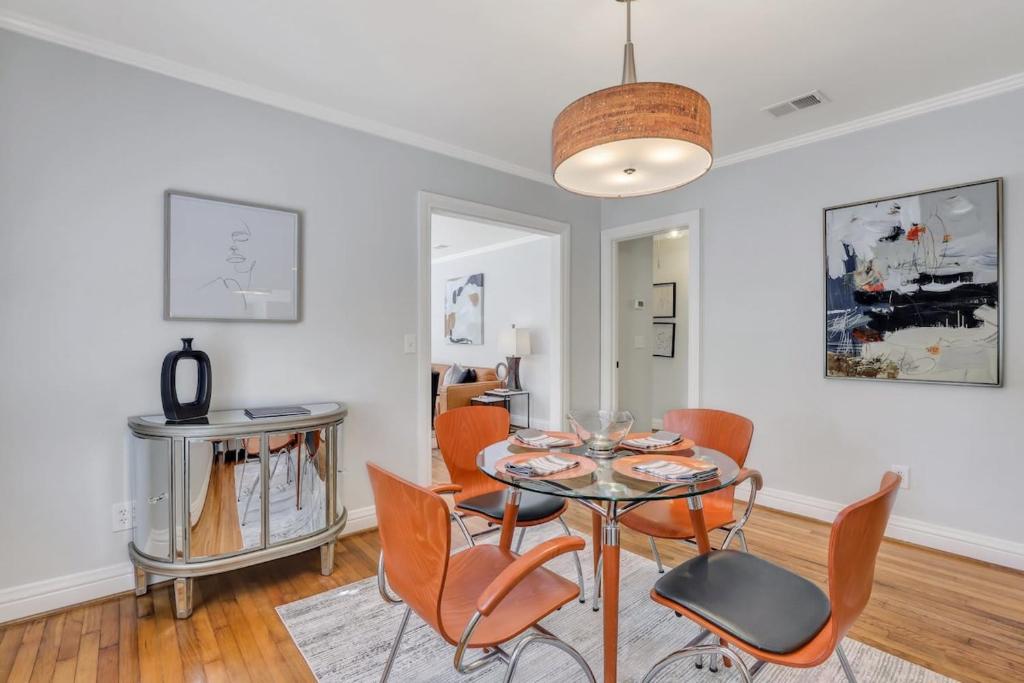 uma sala de jantar com uma mesa de vidro e cadeiras laranja em Mid-Century Bungalow - Blue Mile & Close to GSU em Statesboro