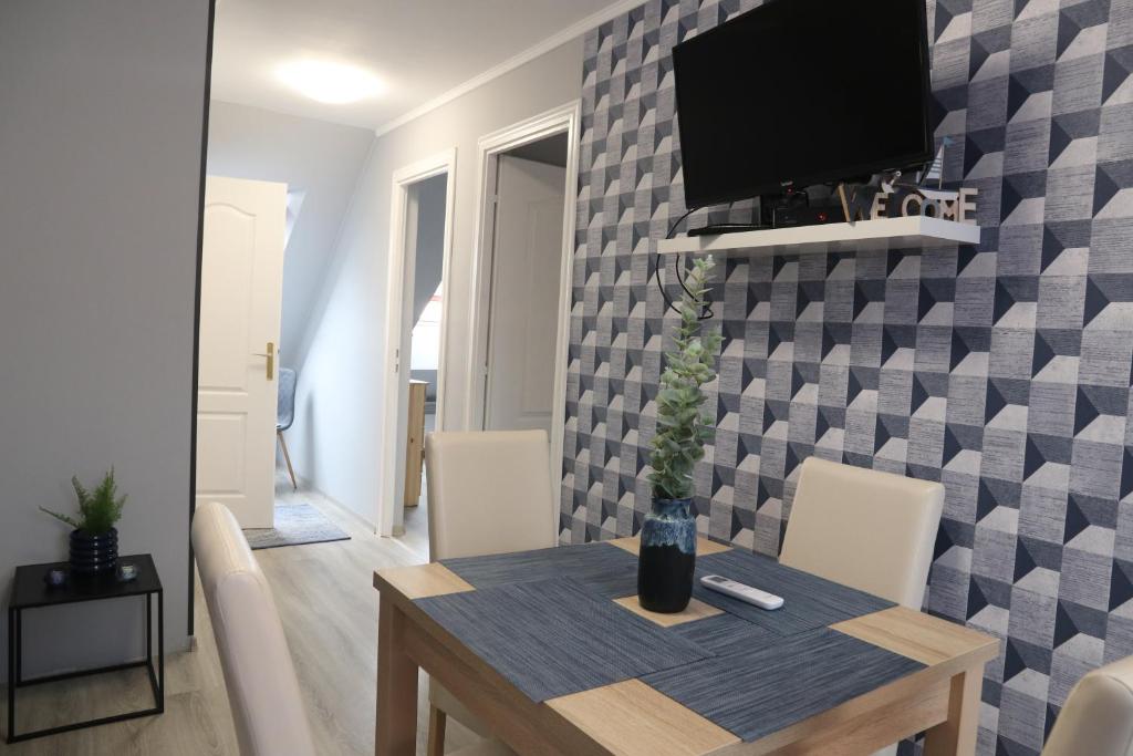 a dining room with a table and a tv on a wall at Várfal apartman II in Eger