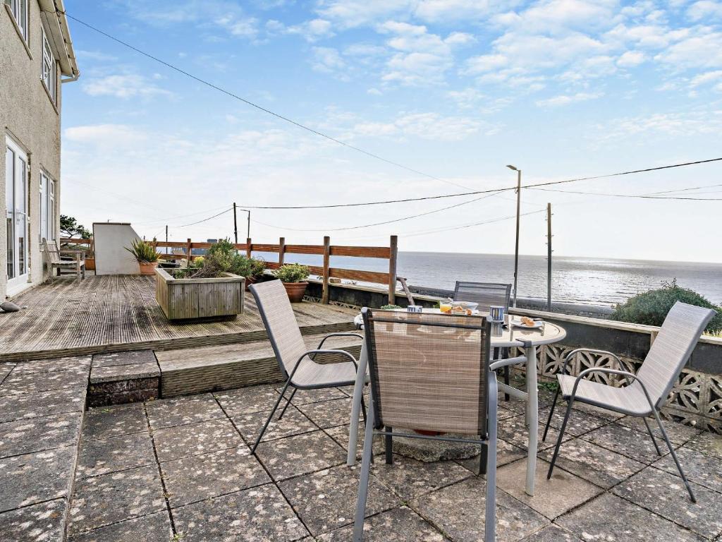a patio with a table and chairs and the ocean at 4 Bed in Ogmore-by-Sea 74236 in Saint Brides Major