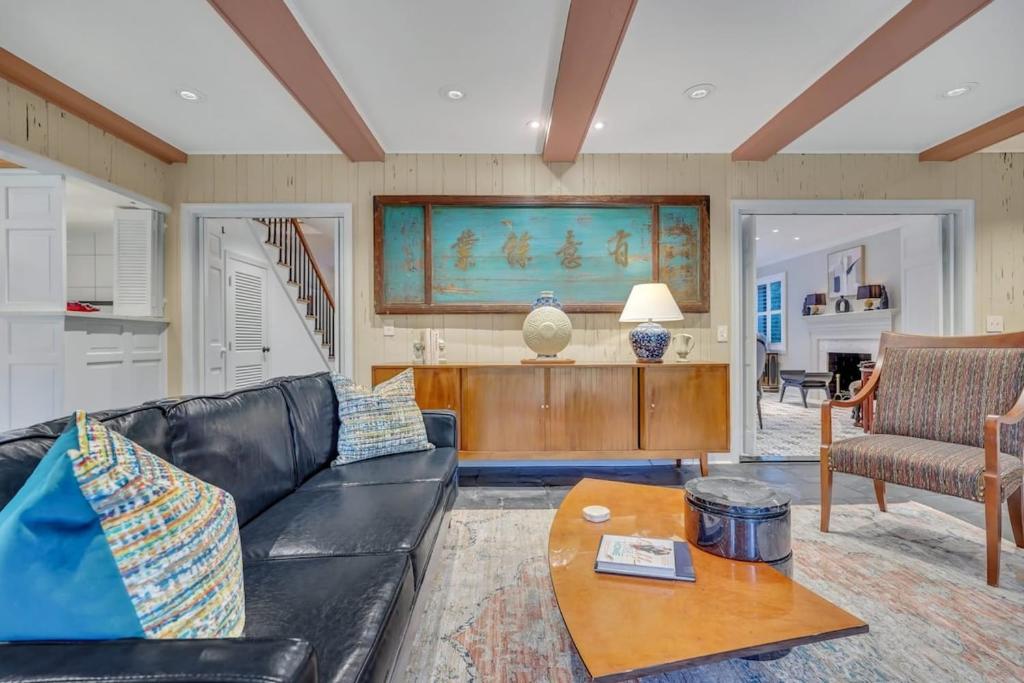 a living room with a black leather couch and a table at The Grey - Large Eclectic and Quiet Home in Statesboro