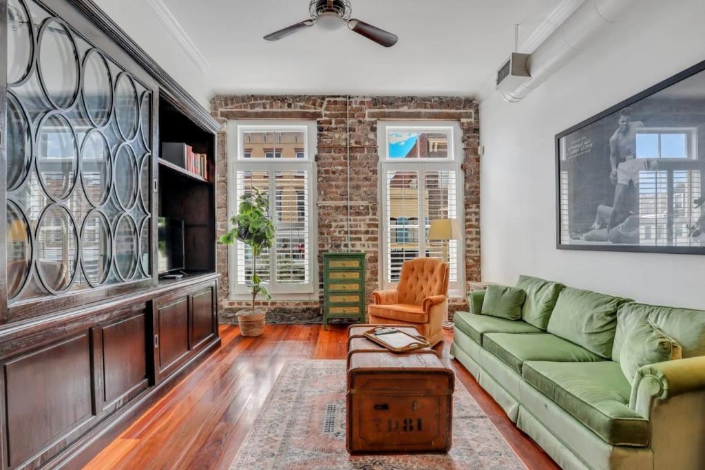 a living room with a green couch and a brick wall at Knockout Loft- Near Plant Riverside in Savannah