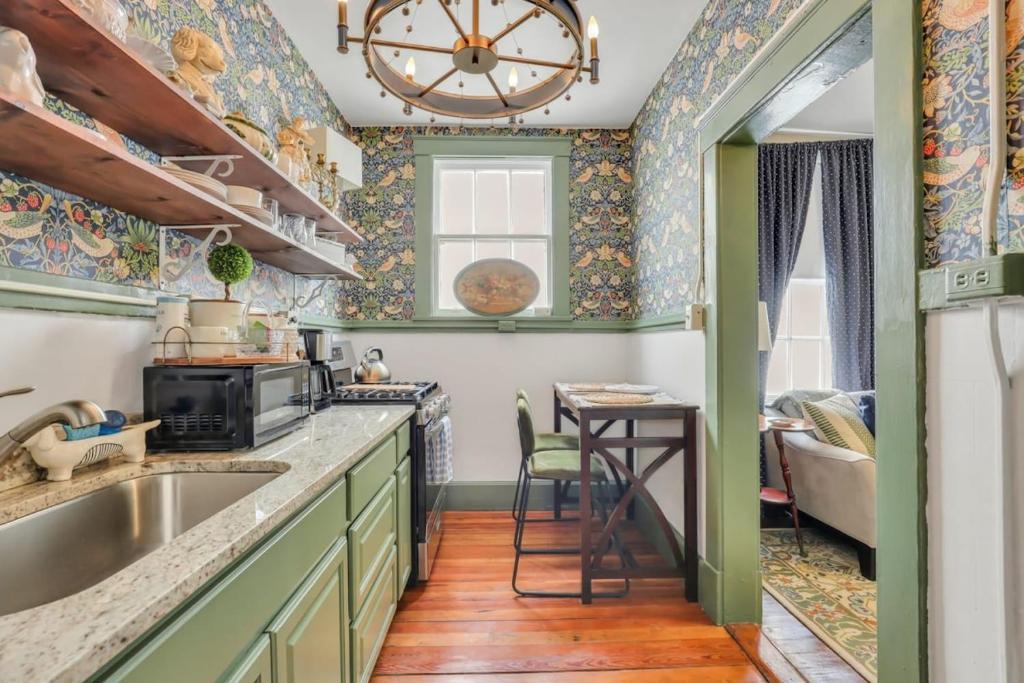 uma cozinha com armários verdes e uma mesa com cadeiras em The Graham on Oglethorpe Square em Savannah
