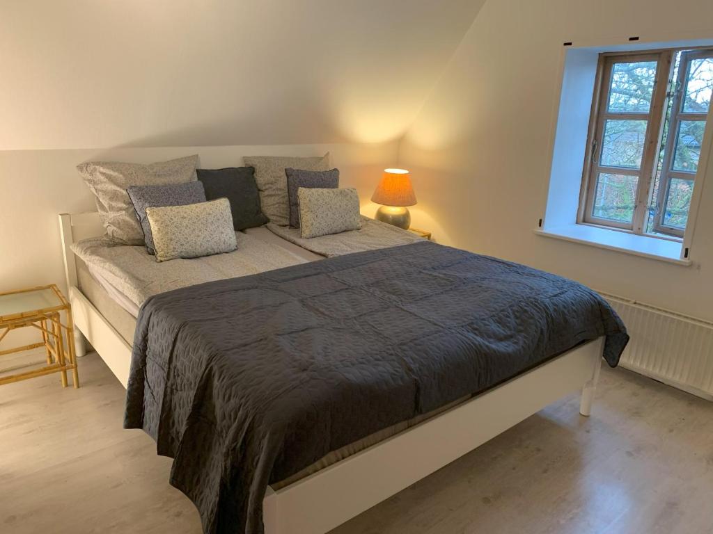 Cette chambre comprend un grand lit et une fenêtre. dans l'établissement Bed & Breakfast “Den Gamle Lade I Hejls”, à Hejls