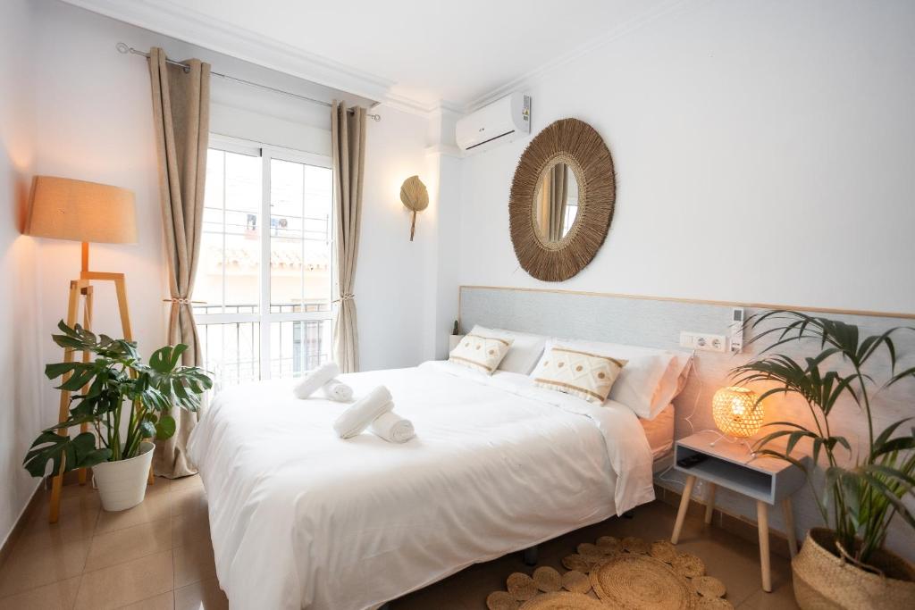um quarto branco com uma cama grande e uma janela em Naim Guest House Nerja em Nerja