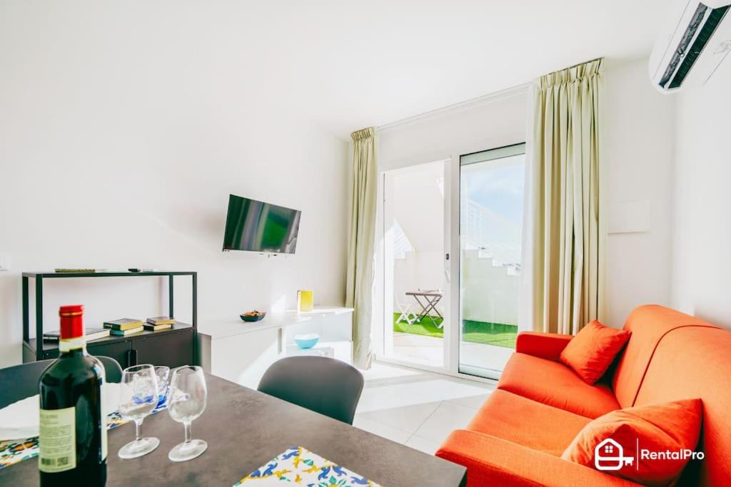 a living room with an orange couch and a table with wine glasses at [Suite Marzamemi] – Near Sea in Marzamemi
