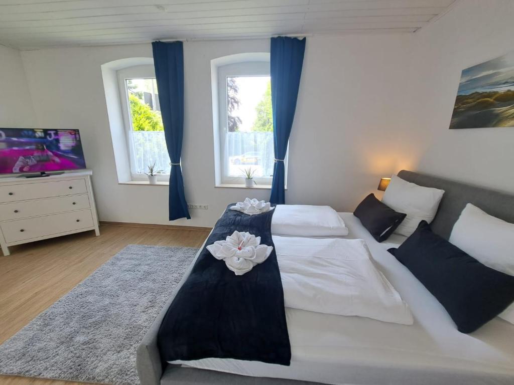 1 Schlafzimmer mit einem großen weißen Bett und 2 Fenstern in der Unterkunft Ferienwohnung Butze Esens in Esens