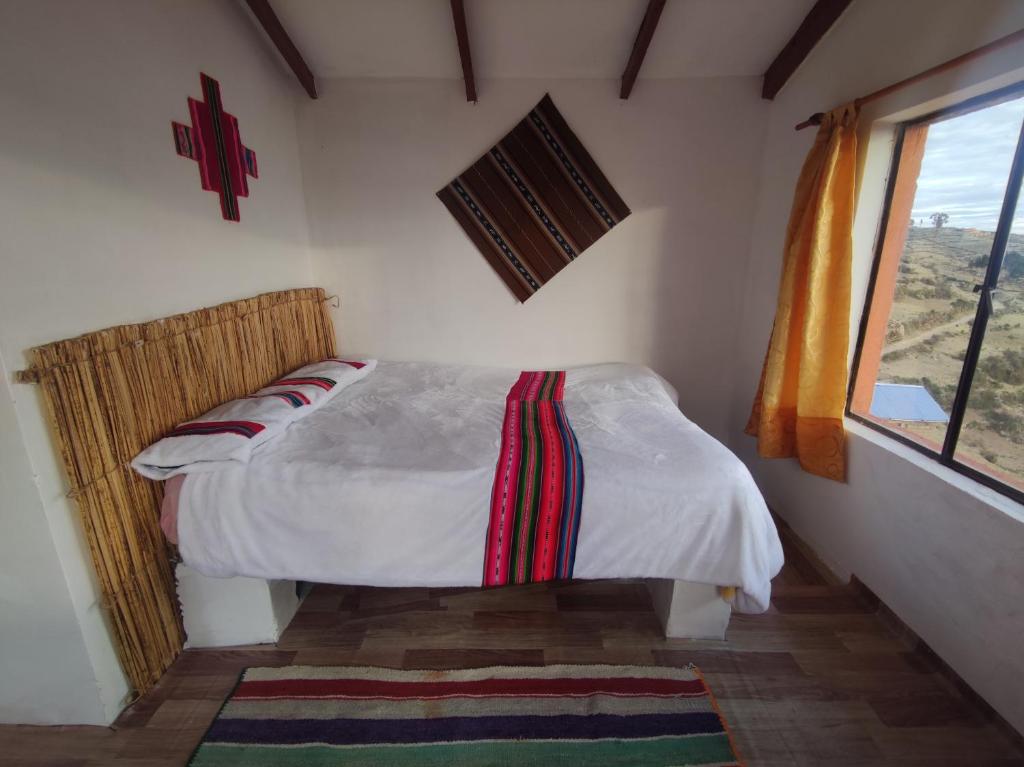 1 dormitorio con 1 cama en una habitación con ventana en INTI WASI LODGE en Comunidad Yumani