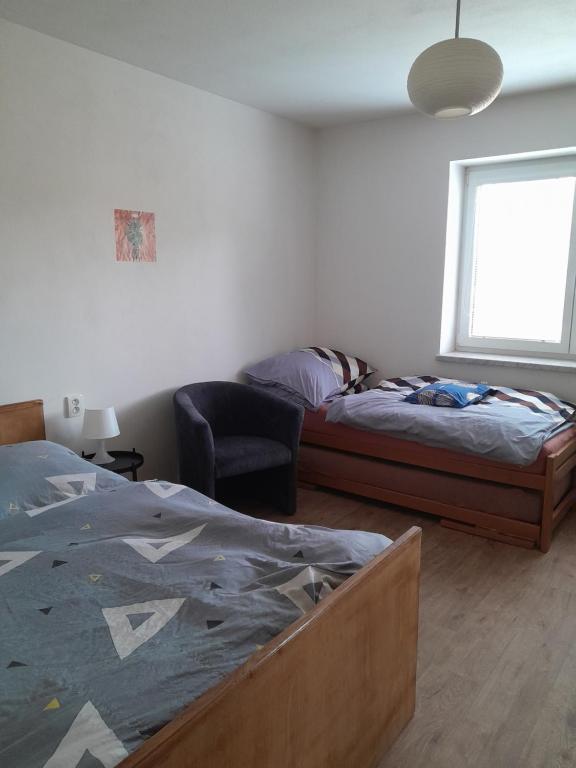 een slaapkamer met een bed, een stoel en een raam bij Ubytování U Pavly in Borovany
