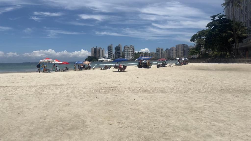 a beach with umbrellas and people on the sand at Joia Da Pitangueiras in Guarujá