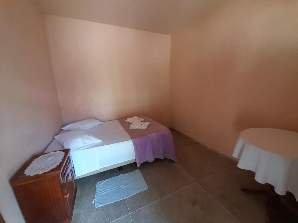 ein kleines Schlafzimmer mit einem Bett und einem Tisch in der Unterkunft Espaço Bella Ville in Caparaó Velho