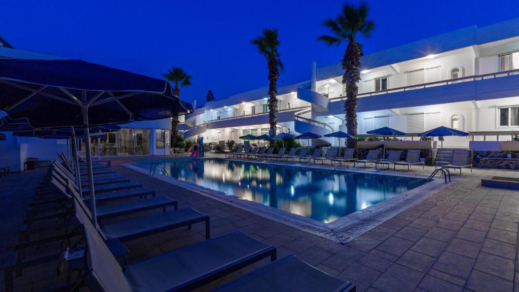 a swimming pool in front of a building at night at Paleos Hotel Apartments in Ialyssos