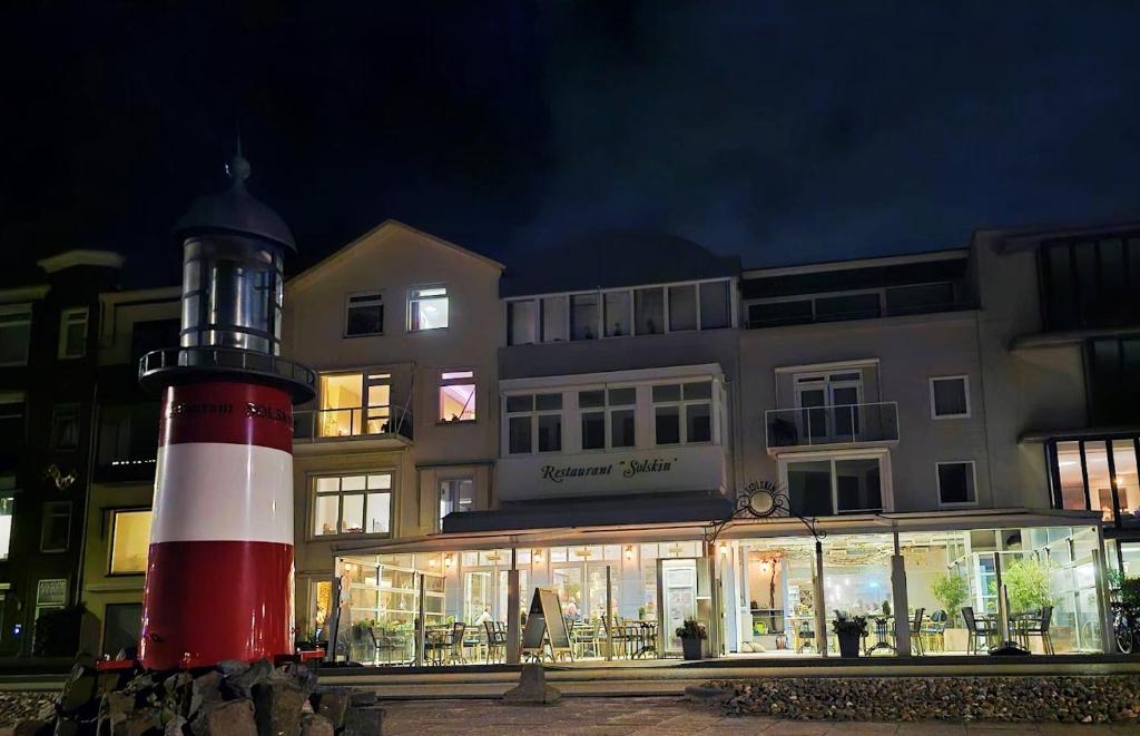 een rode en witte vuurtoren voor een gebouw bij Hotel Restaurant Solskin in Vlissingen