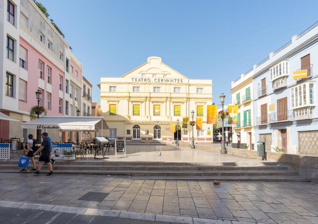 Un uomo che cammina per una strada di fronte a un edificio di Teatro Plaza Apartments a Málaga