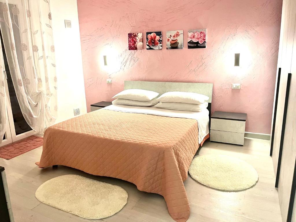 um quarto rosa com uma cama com 2 almofadas em Stefy's House em Scalea