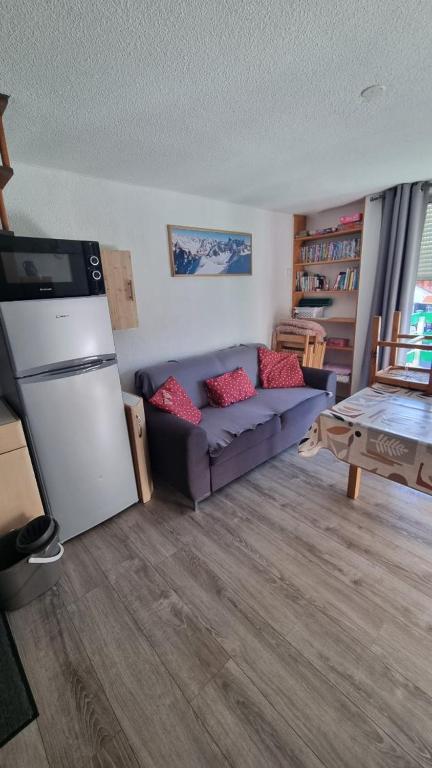- un salon avec un canapé bleu et un réfrigérateur dans l'établissement Triplex pieds des pistes st lary Soulan, à Saint-Lary-Soulan