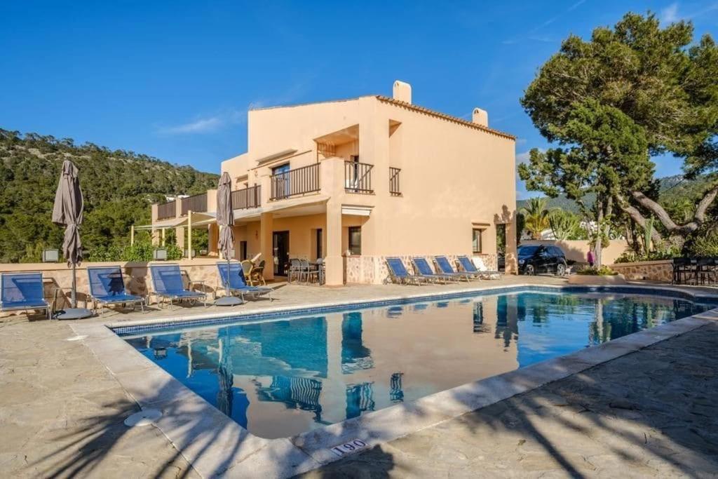 a villa with a swimming pool in front of a house at Casa en Cala Vadella con piscina y vistas al mar in Sant Josep de sa Talaia